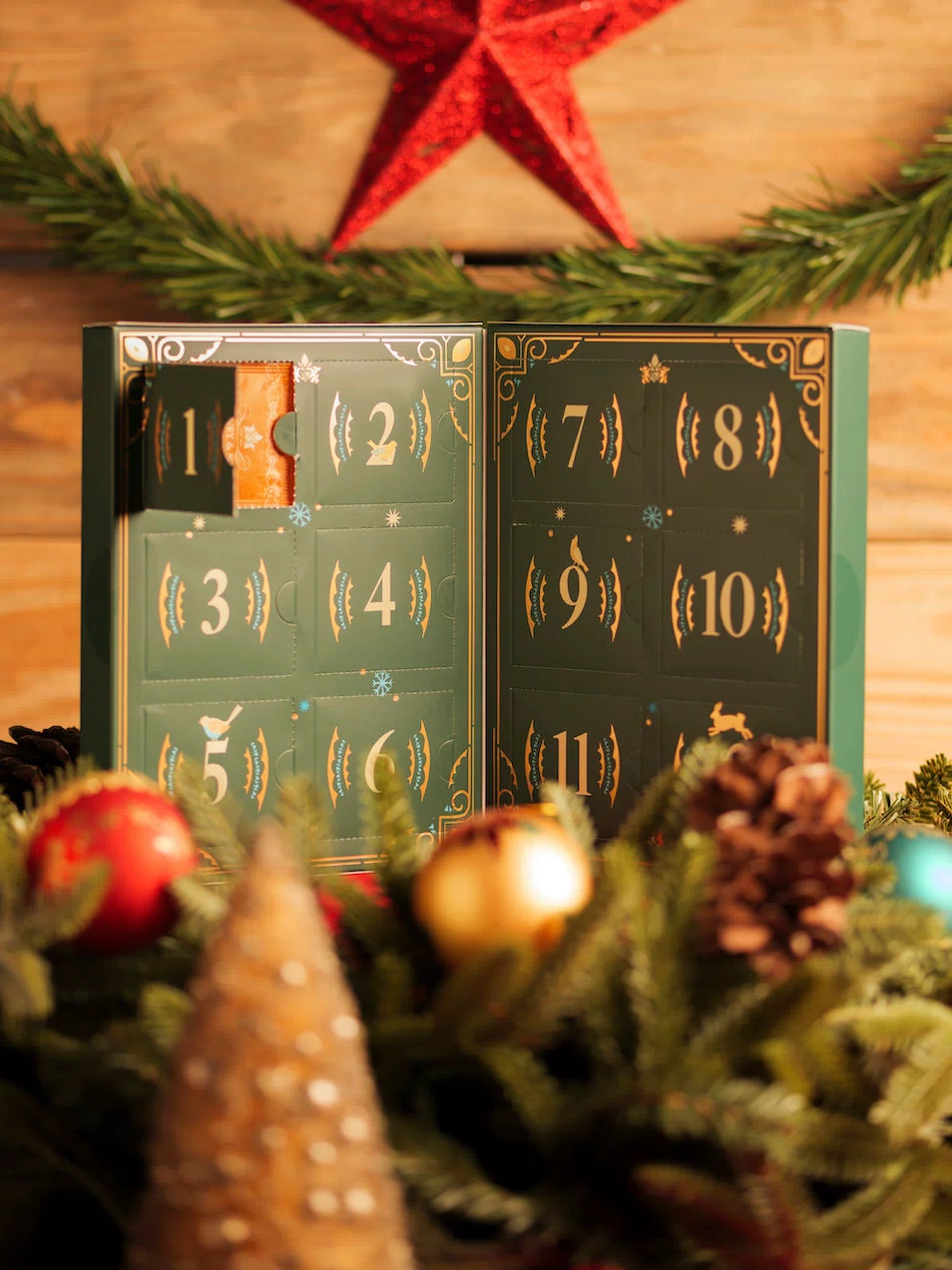 Advent calendar with numbered doors on a wooden background with Christmas decorations.
