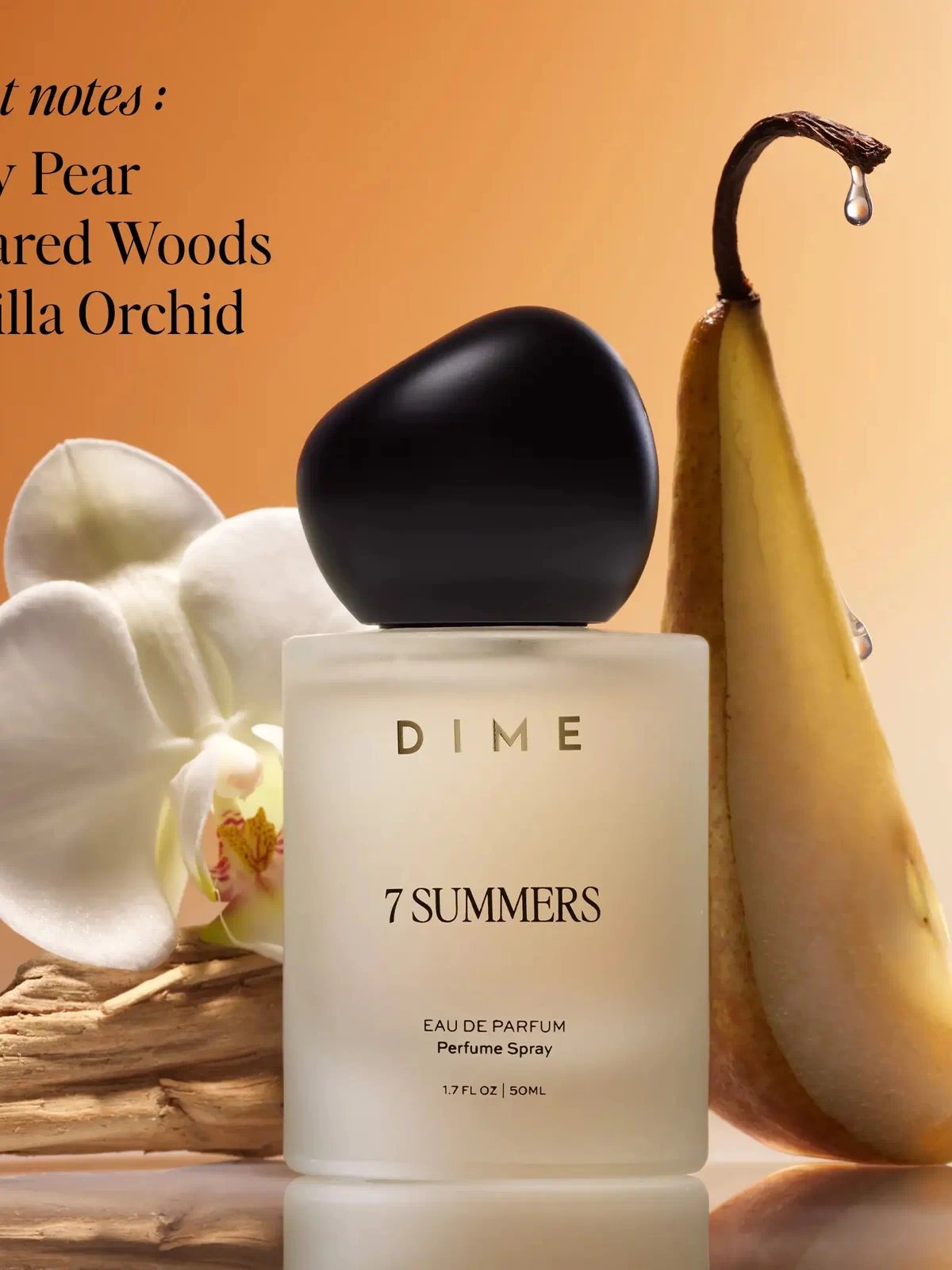 White cylindrical perfume bottle with black cap, 50ml, surrounded by white orchid flowers, driftwood, and a pear-shaped decor