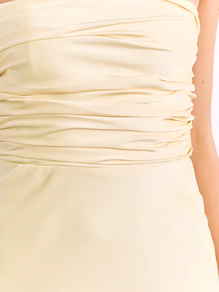 Close-up of the horizontally ruched bodice and smooth lower section of a yellow maxi dress