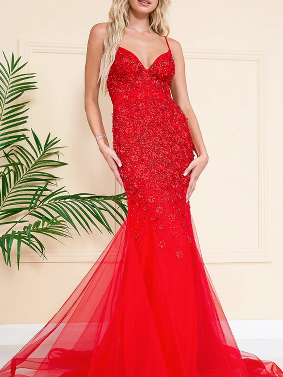 A woman wearing the Floral-Embellished Long Prom Dress with Train SU066 stands indoors beside a potted plant. The fitted dress features intricate floral embellishments, a floor-length mermaid silhouette, and an elegant train.