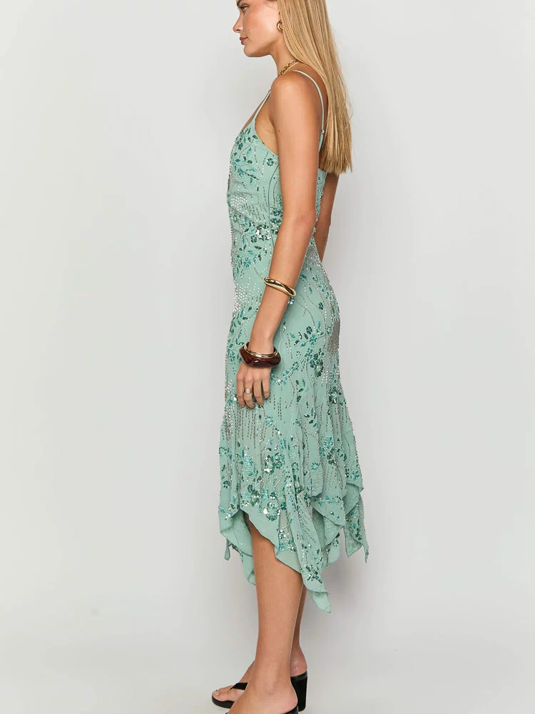 Side view of a teal sequin midi dress with spaghetti straps and a flowy asymmetrical handkerchief hem