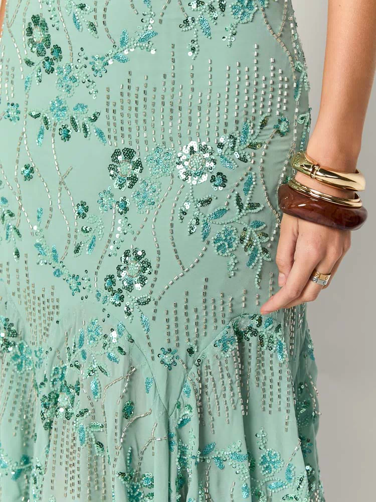Close-up of the mint green sequin midi dress showing intricate teal floral embroidery, silver beading, and flared hem