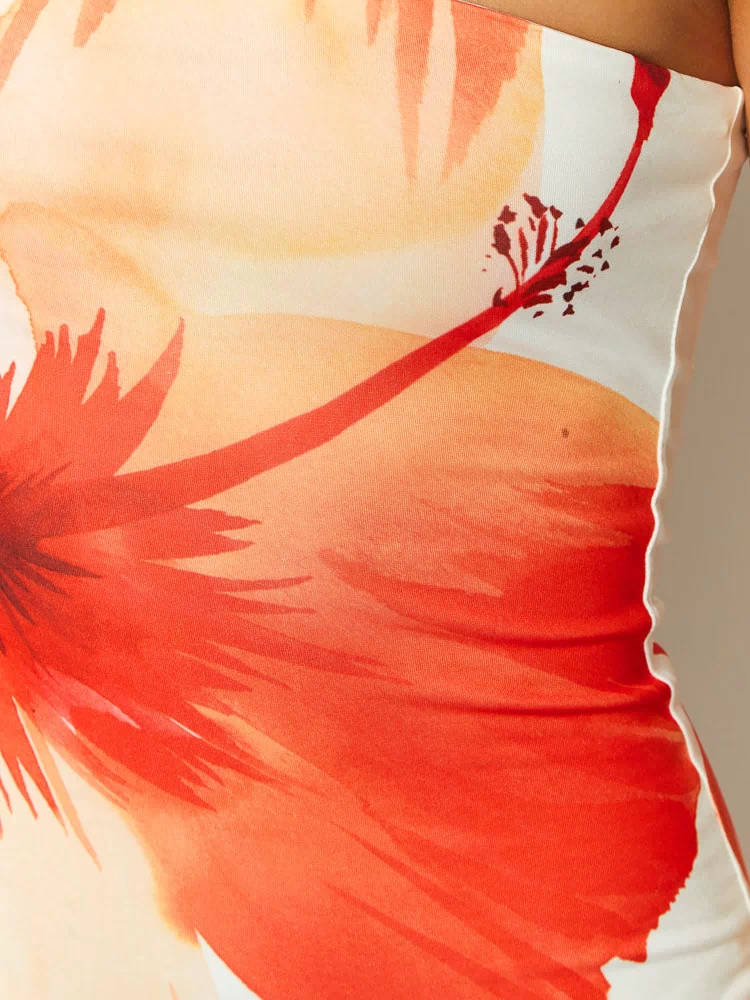 Close-up of the white maxi dress fabric, showing the large orange and red floral print and wavy lettuce hem
