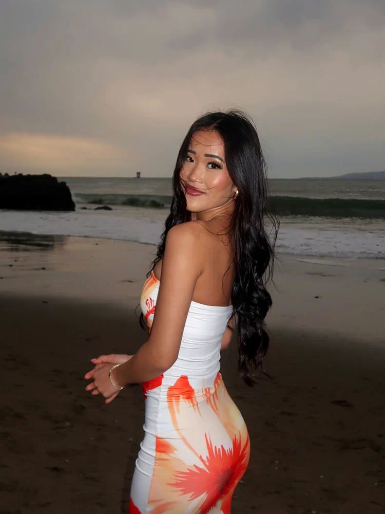 Side view of the white strapless maxi dress showing the large orange floral print on the hip