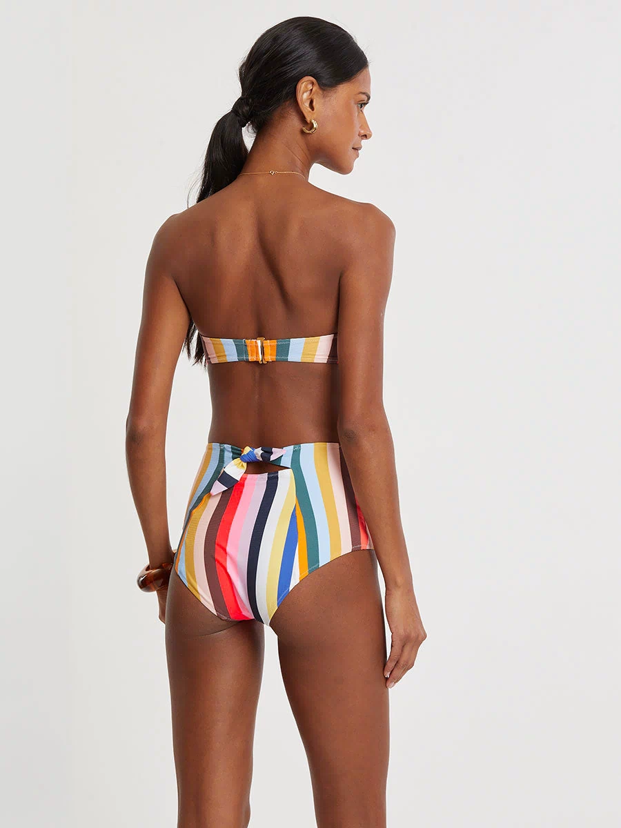 Woman wearing lemlem AVA Bandeau Top and ELSI High Waist Bottom  featuring bold, joyful stripe pattern in vibrant shades of blue, yellow, pink, orange, and green