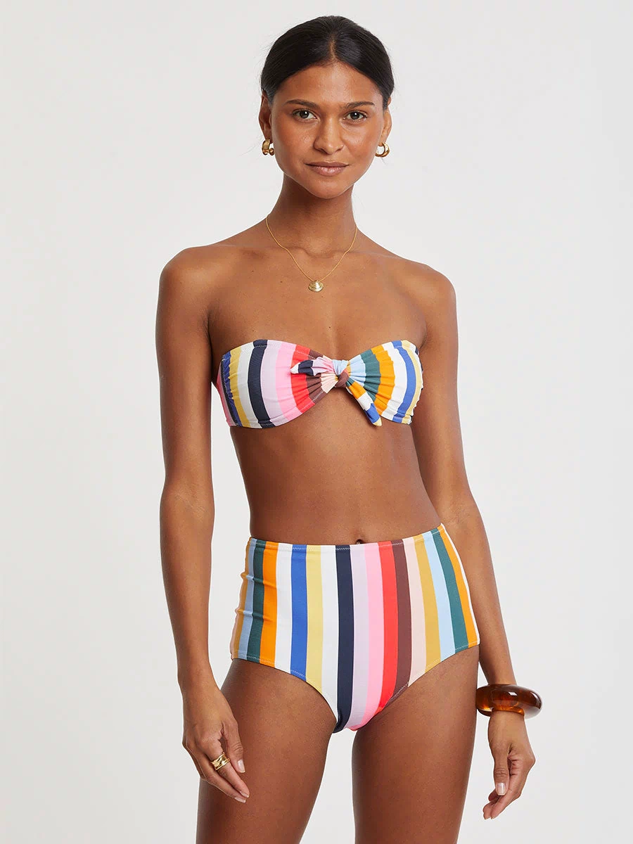 Woman wearing lemlem AVA Bandeau Top and ELSI High Waist Bottom  featuring bold, joyful stripe pattern in vibrant shades of blue, yellow, pink, orange, and green