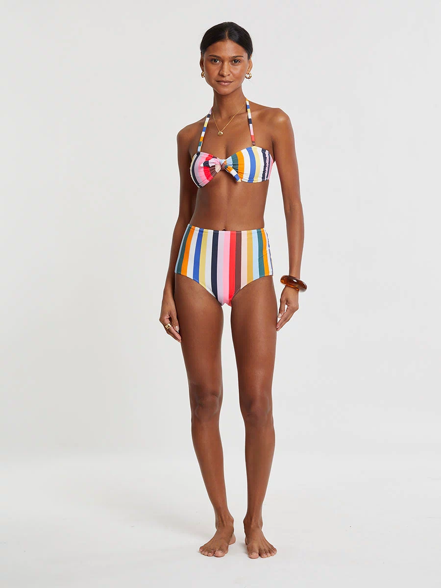 Woman wearing lemlem AVA Bandeau Top and ELSI High Waist Bottom  featuring bold, joyful stripe pattern in vibrant shades of blue, yellow, pink, orange, and green