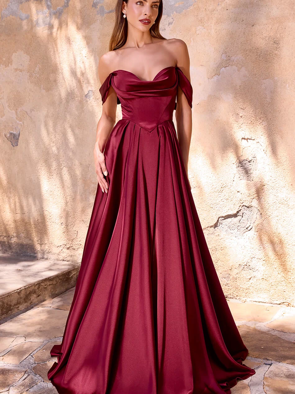 Woman wearing a burgundy evening gown against a textured wall.