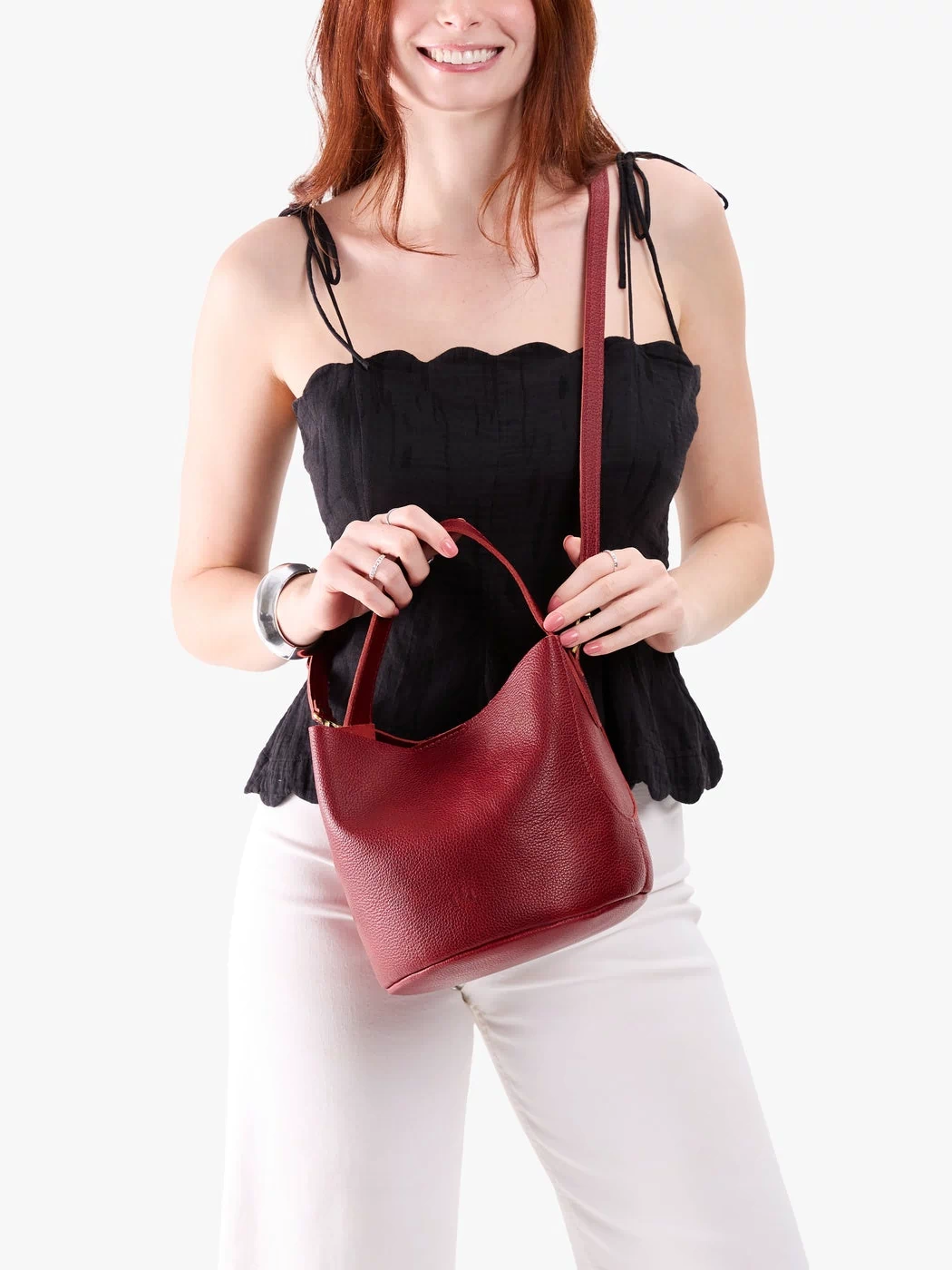 Chili Red*Small | Model holding symmetrical bucket bag with handle, latch closure, and removable crossbody strap