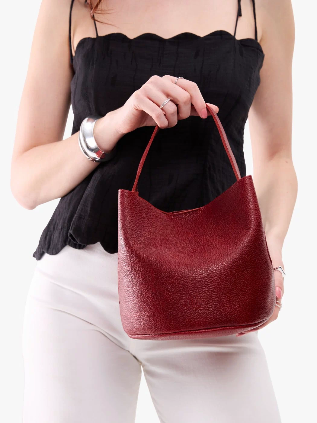 Chili Red*Small | Model holding symmetrical bucket bag with handle, latch closure, and removable crossbody strap