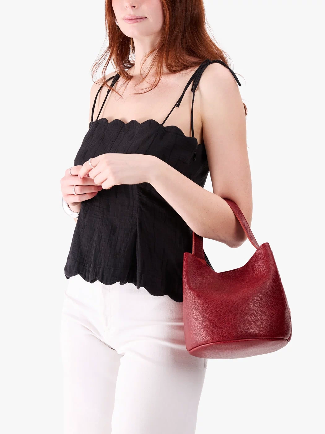 Chili Red*Small | Model carrying symmetrical bucket bag with handle, latch closure, and removable crossbody strap