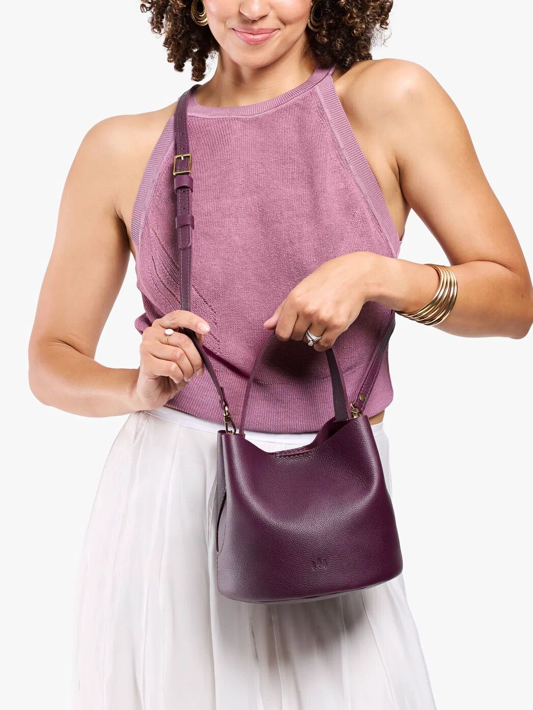 Plum*Small | Model wearing symmetrical bucket bag with handle, latch closure, and removable crossbody strap