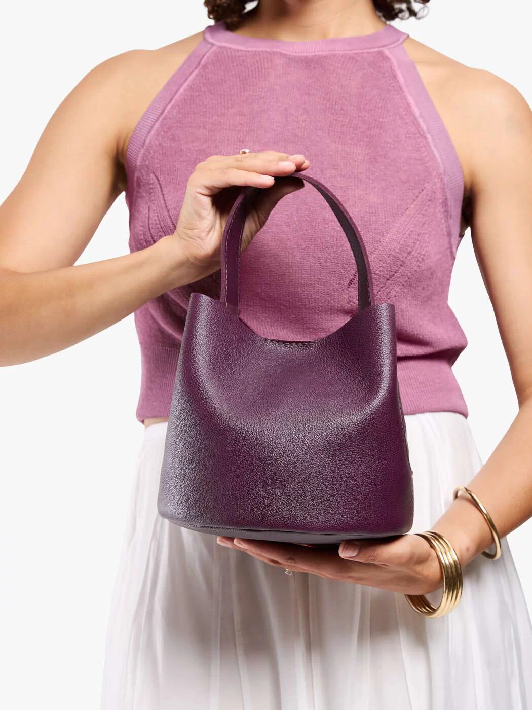 Plum*Small | Model holding symmetrical bucket bag with handle, latch closure, and removable crossbody strap