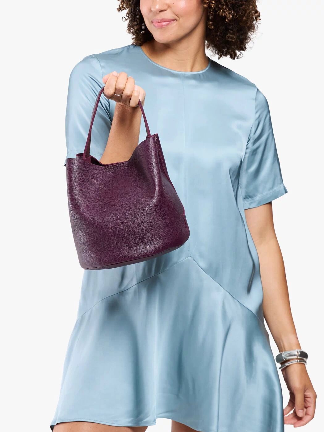 Plum*Large | Model carrying symmetrical bucket bag with handle, latch closure, and removable crossbody strap