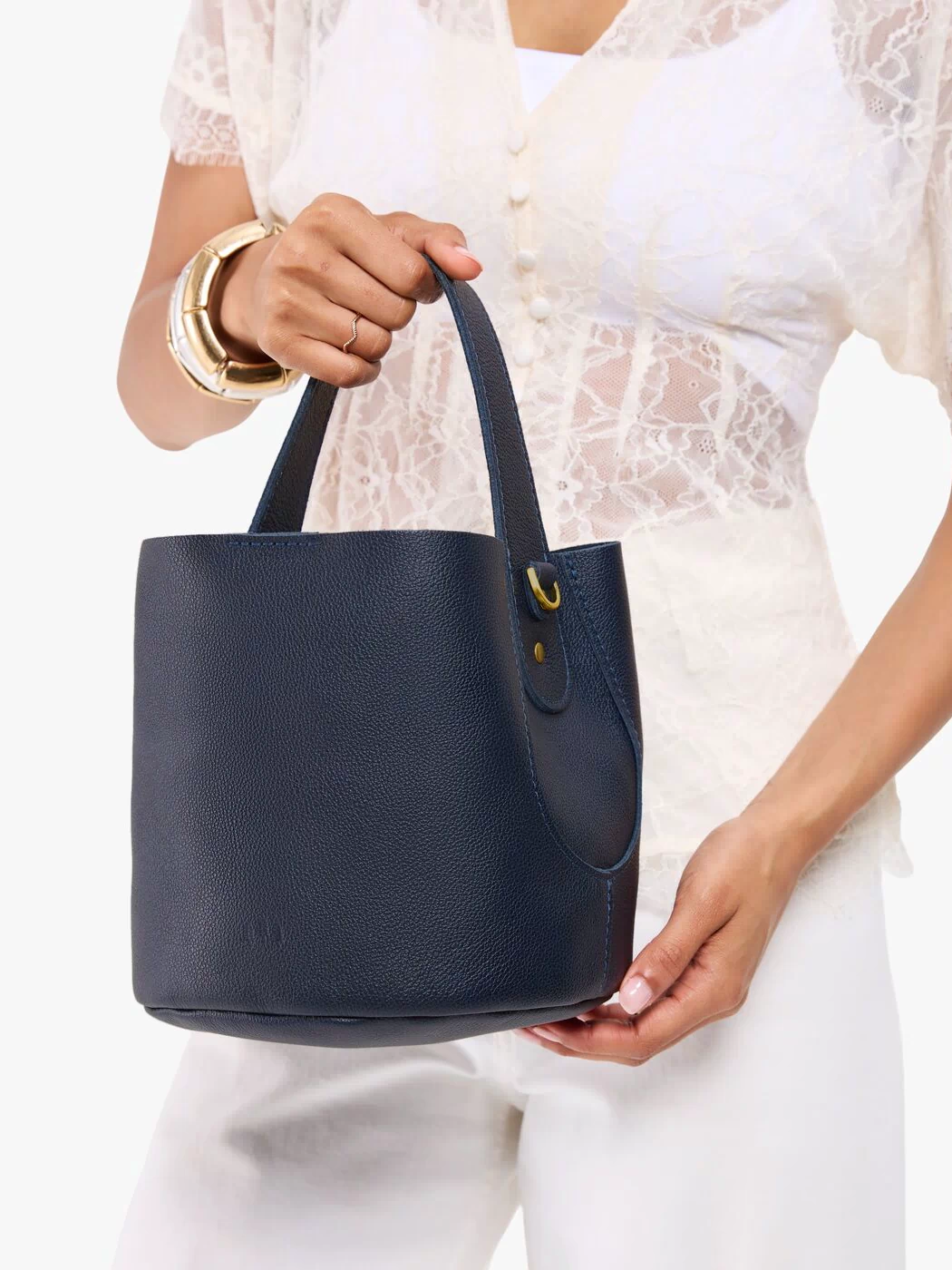 Night Owl*Small | Model carrying symmetrical bucket bag with handle, latch closure, and removable crossbody strap