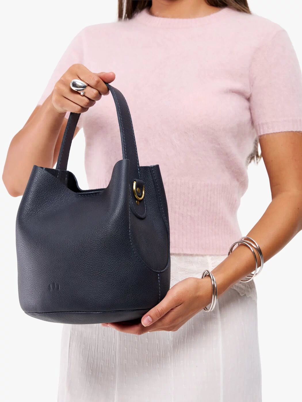 Night Owl*Large | Model carrying symmetrical bucket bag with handle, latch closure, and removable crossbody strap