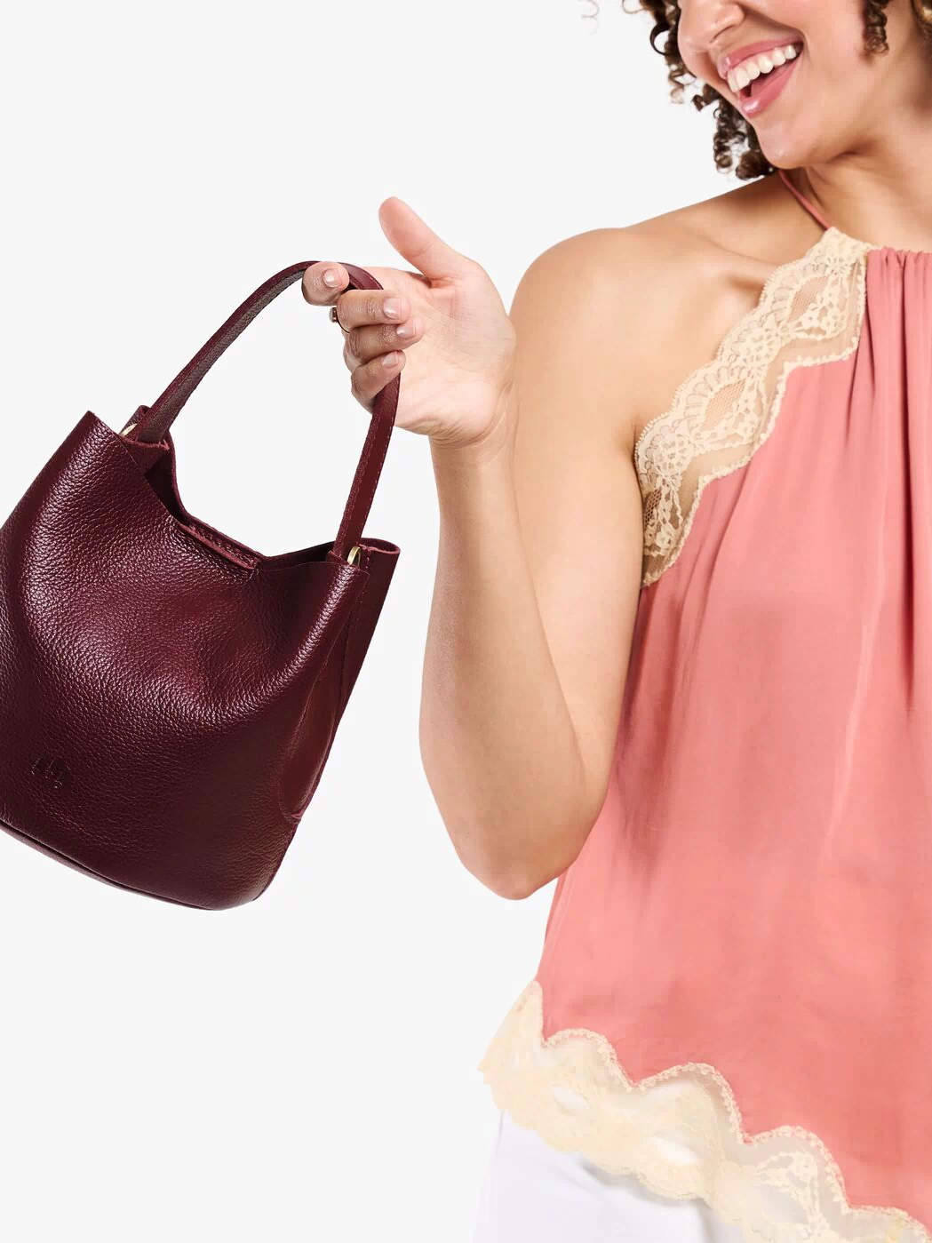 Cabernet*Small | Model carrying symmetrical bucket bag with handle, latch closure, and removable crossbody strap