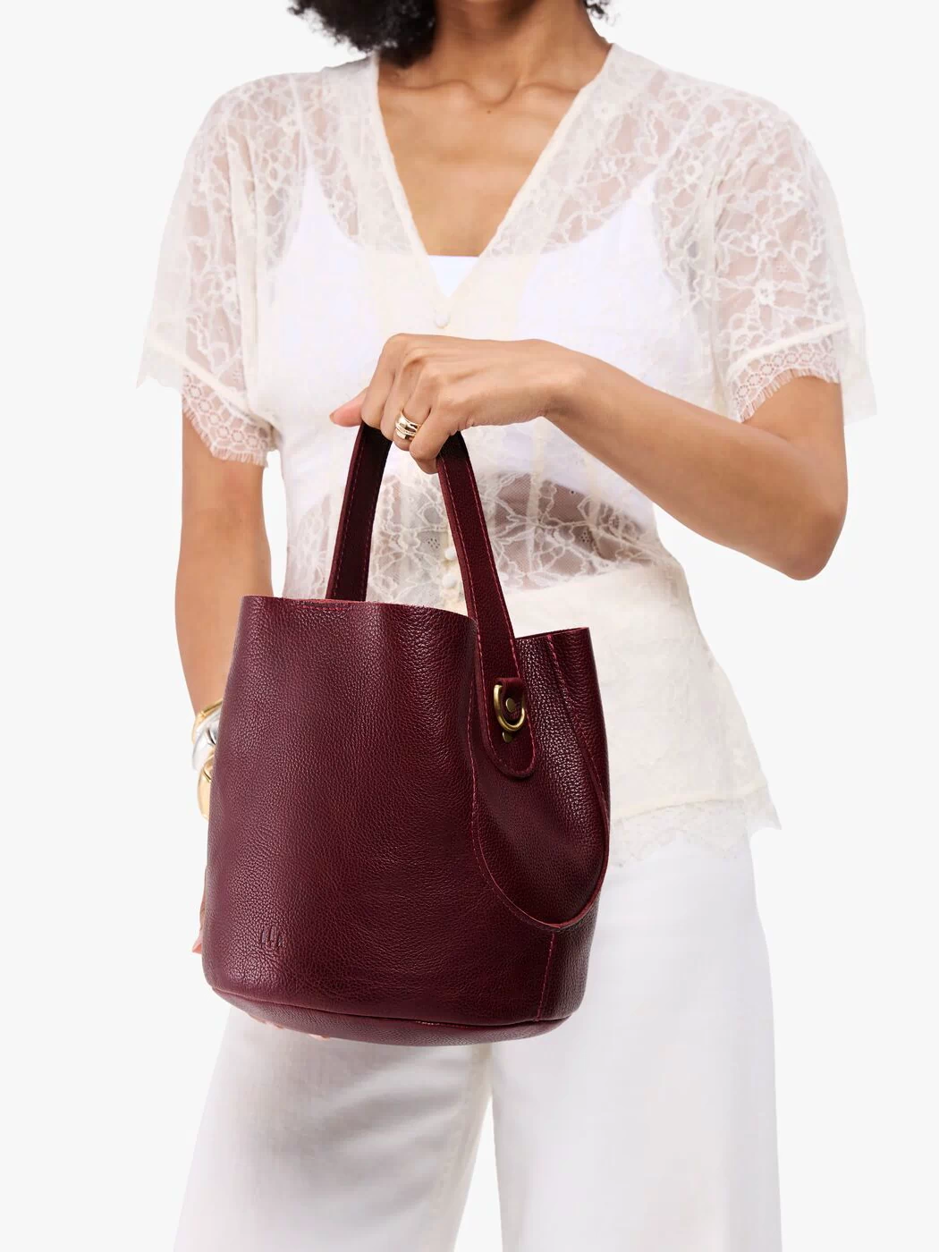 Cabernet*Large | Model carrying symmetrical bucket bag with handle, latch closure, and removable crossbody strap