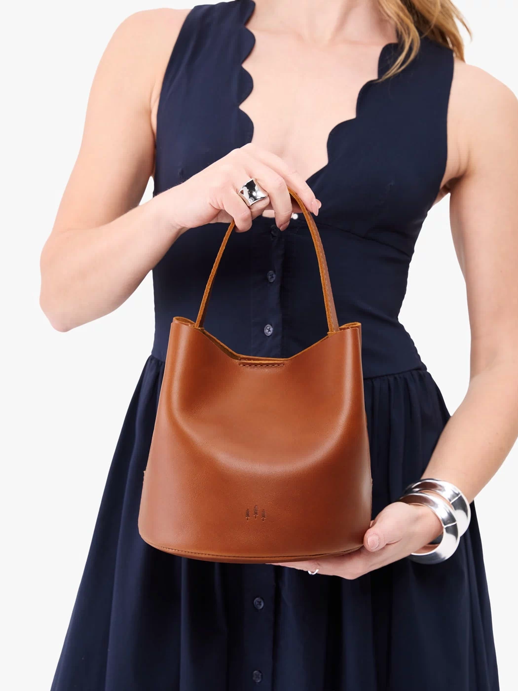 Honey*Small | Model holding symmetrical bucket bag with handle, latch closure, and removable crossbody strap