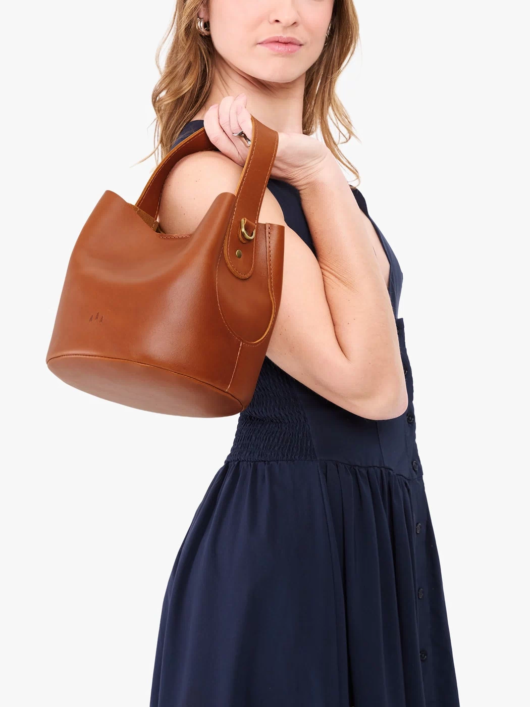 Honey*Small | Model holding symmetrical bucket bag with handle, latch closure, and removable crossbody strap