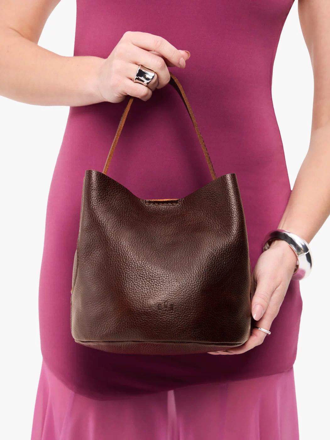 Coldbrew*Small | Model holding symmetrical bucket bag with handle, latch closure, and removable crossbody strap