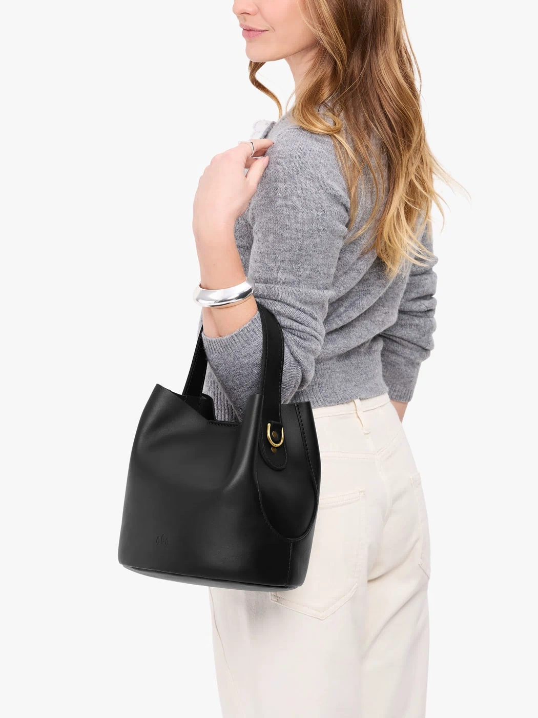 Black*Large | Model carrying symmetrical bucket bag with handle, latch closure, and removable crossbody strap