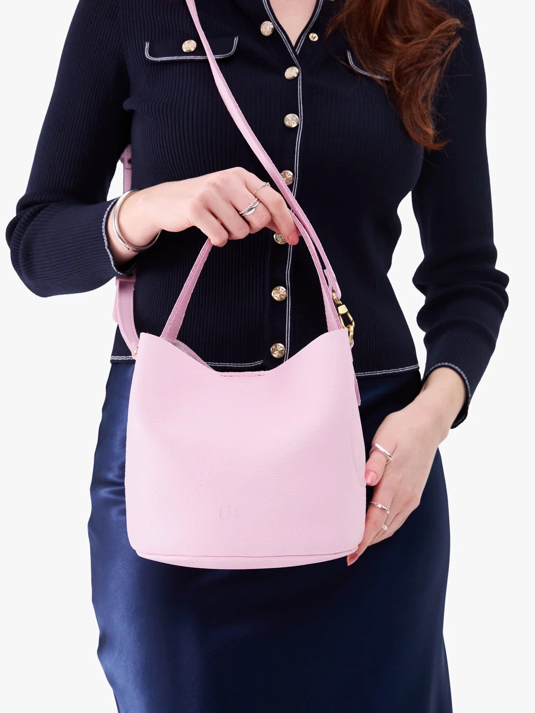 Pinkaboo*Small | Model holding symmetrical bucket bag with handle, latch closure, and removable crossbody strap