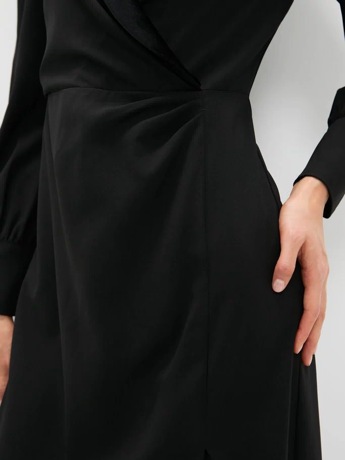 Black Long Sleeve Mariella Midi Dress with velvet trim, side gather, and blouson sleeves, showcasing classic, effortless style. Hand demonstrates side pocket, highlighting its high-end, fun design.