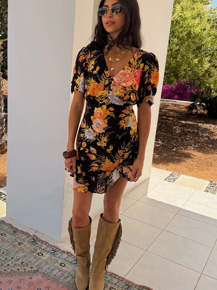 Black Sofia Mini Tea Dress with a vibrant floral print, puff sleeves and a frilled hem, paired with tan fringe boots.