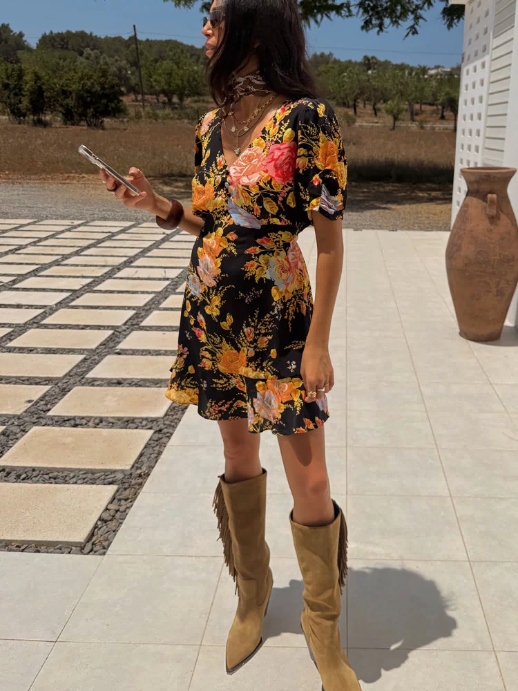 Black Sofia Mini Tea Dress with an orange and pink floral print and frill hem, styled with tan fringe boots.
