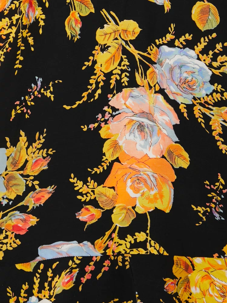 Black Sofia Mini Tea Dress detail highlighting the intricate orange and yellow floral print on a black base.