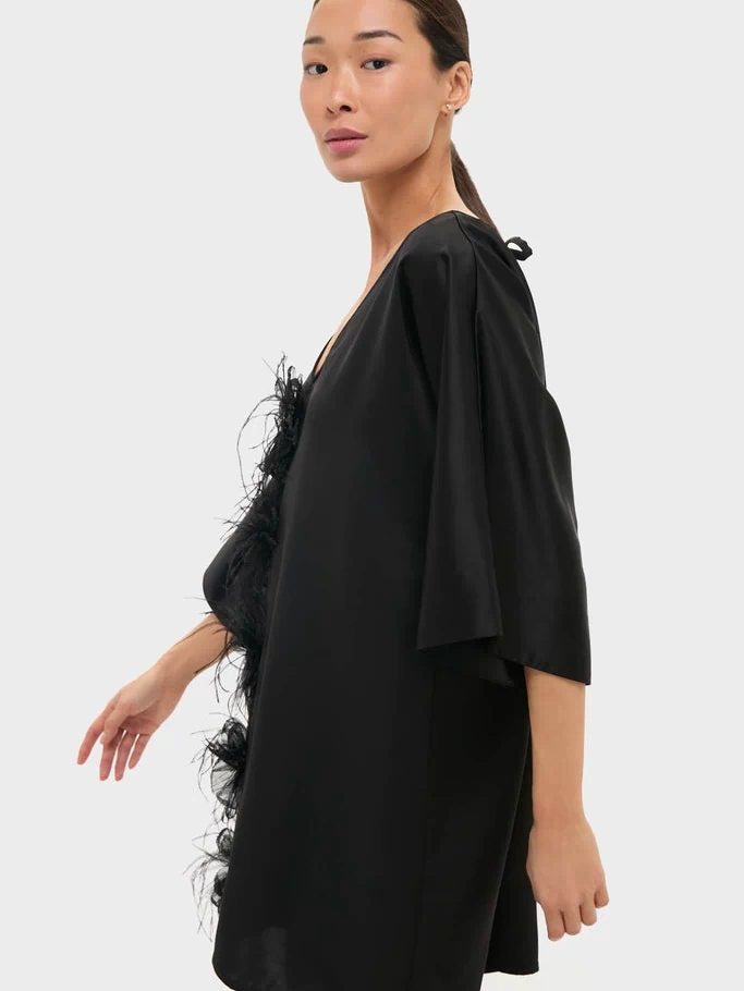 Woman wearing Black Satin Diane Mini Dress with three-quarter kimono sleeves and feather floral trim, showcasing a classic, effortless style for high-end events.