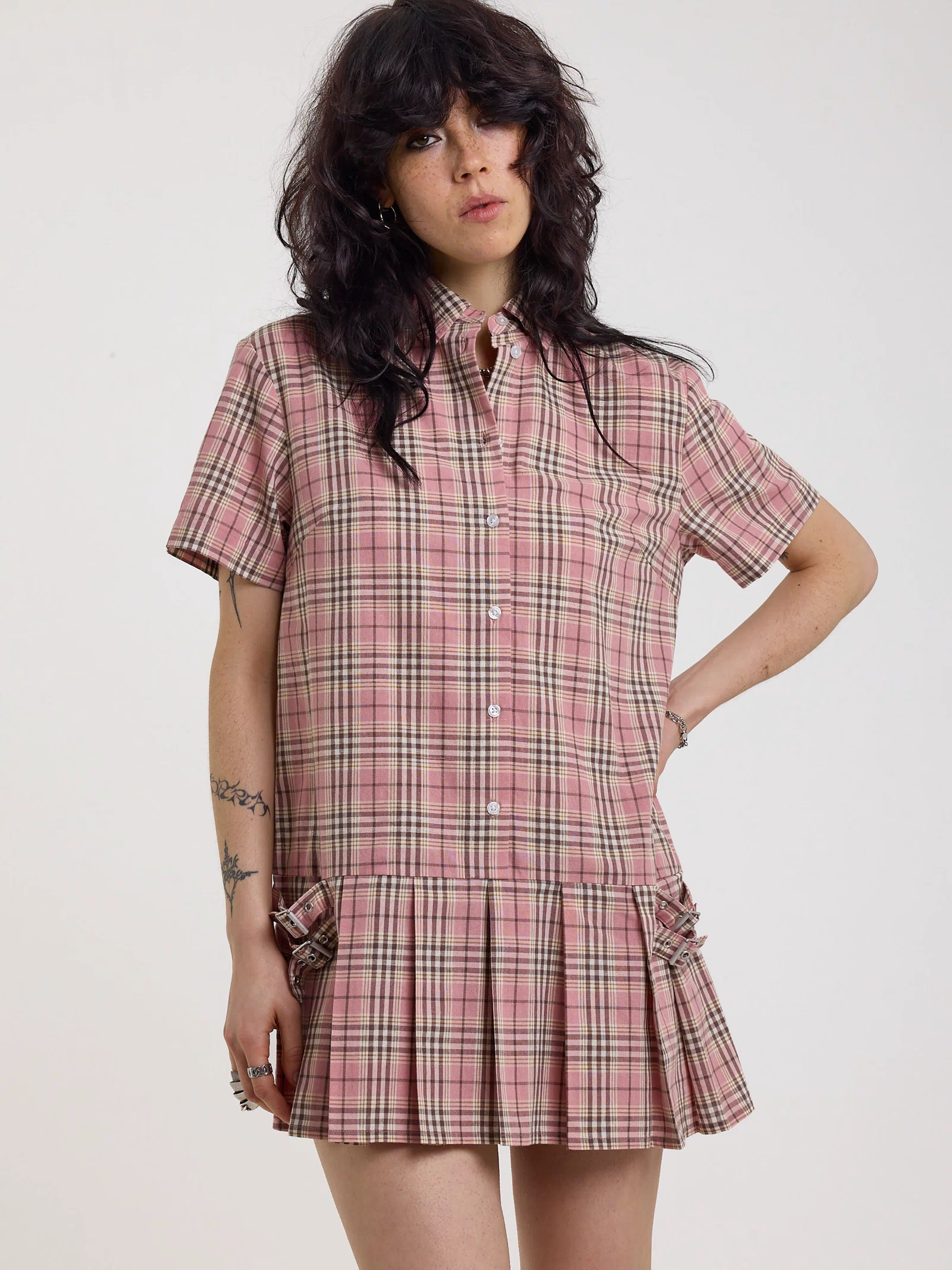 Pink tartan check mini dress with pleated mini skirt buttons, collar and silver buckle detail, worn by model