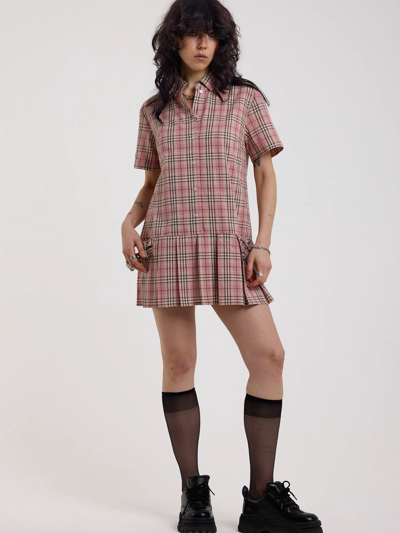 Pink tartan check mini dress with pleated mini skirt buttons, collar and silver buckle detail, worn by model
