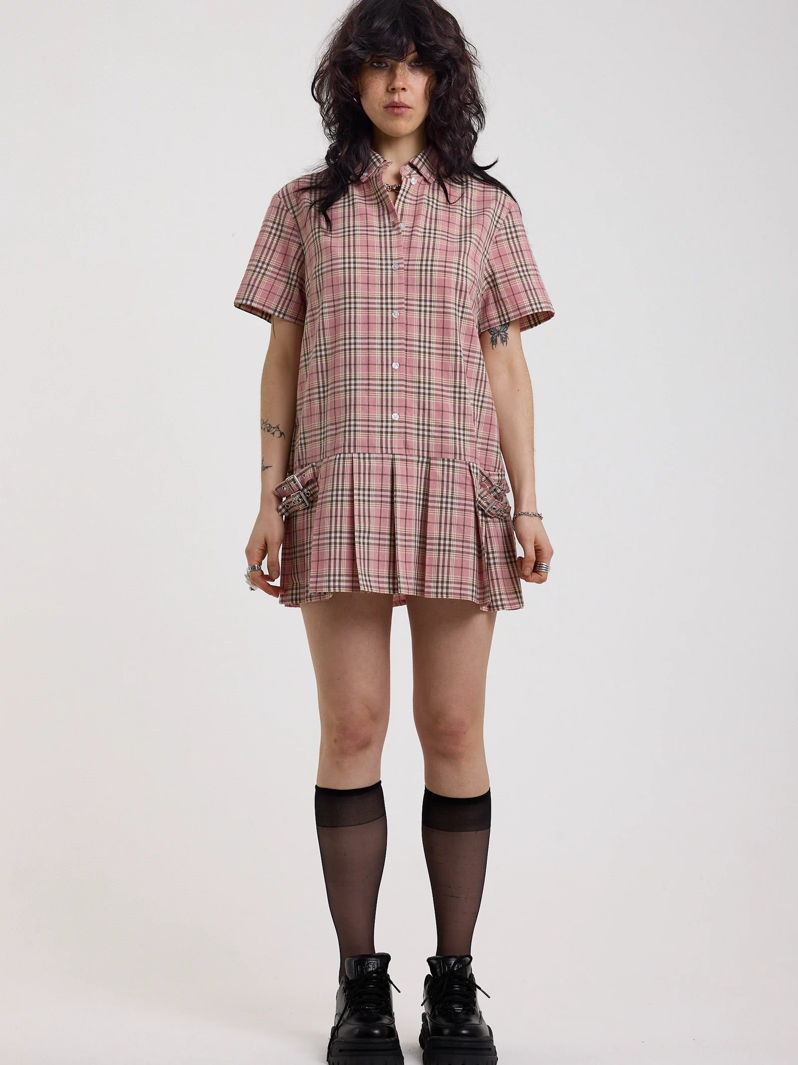 Pink tartan check mini dress with pleated mini skirt buttons, collar and silver buckle detail, worn by model