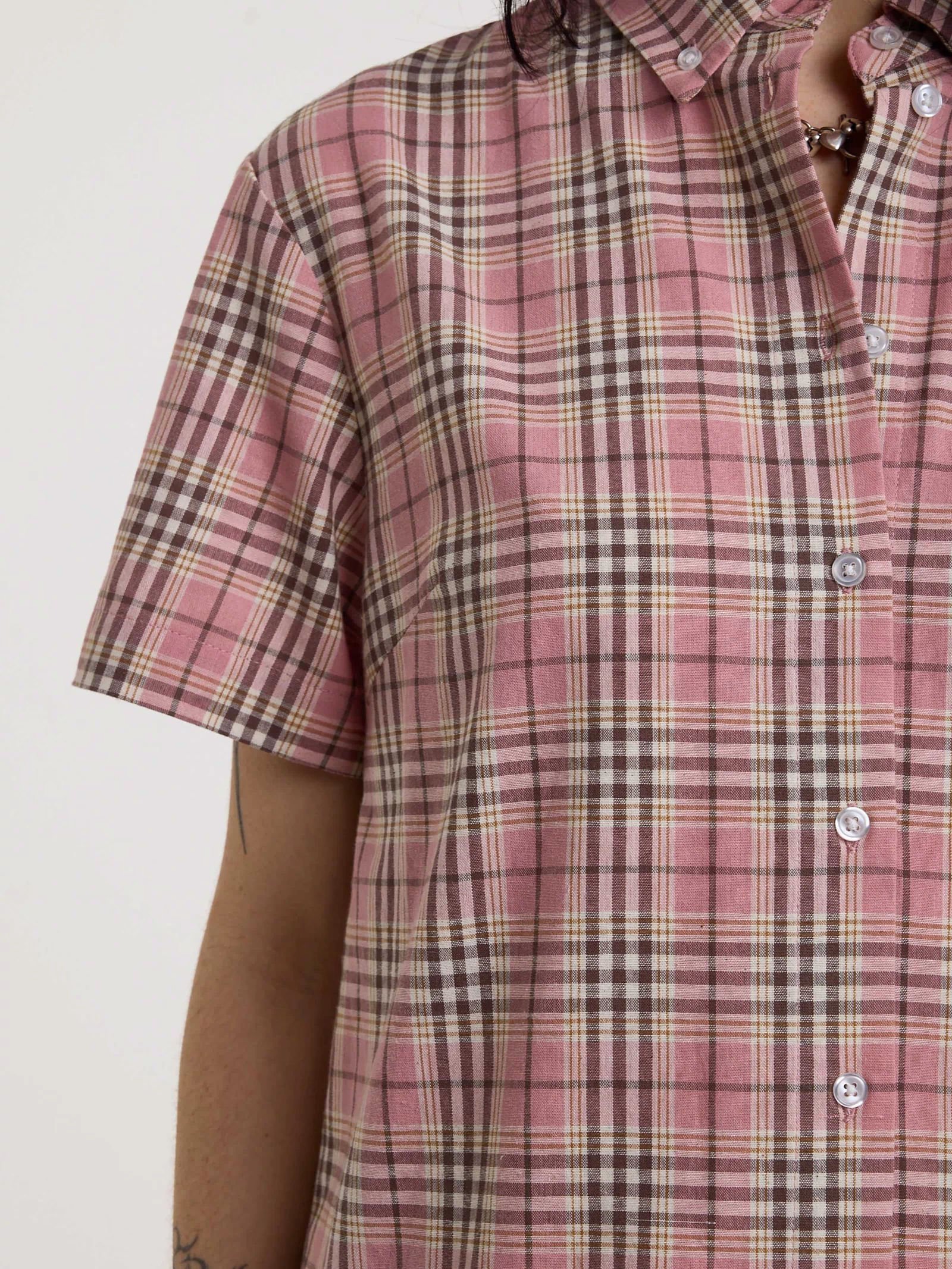 Close up of pink tartan check, short sleeves and button down collar on mini dress, worn by model