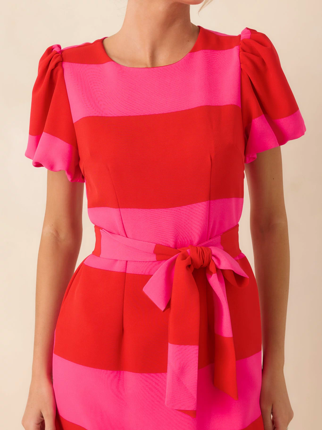 Close-up of the red and pink stripe pattern, puff sleeve detail, and removable waist tie on the dress.