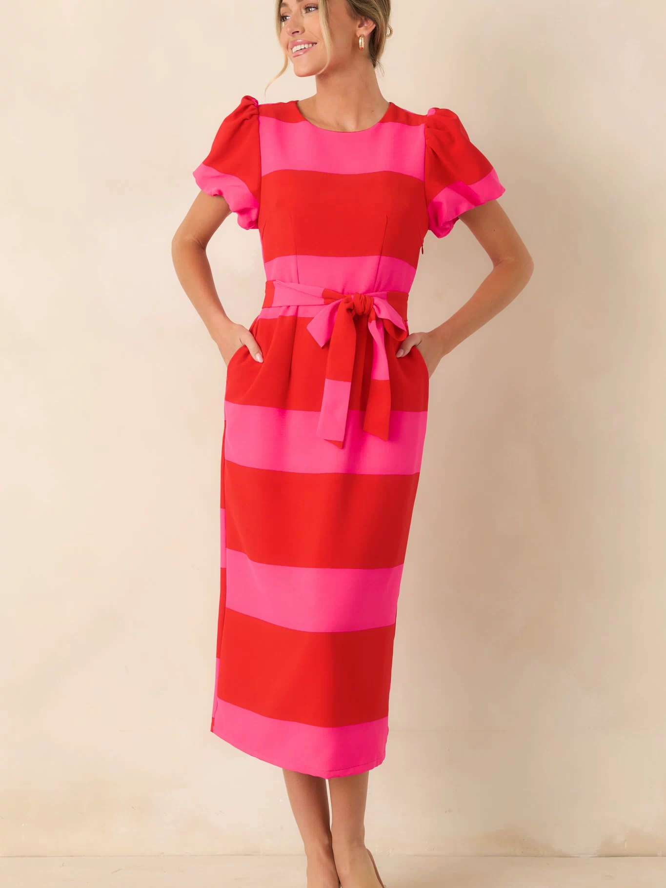 Red and pink dress with bold stripes, a flattering waist tie, and a polished midi-length silhouette.