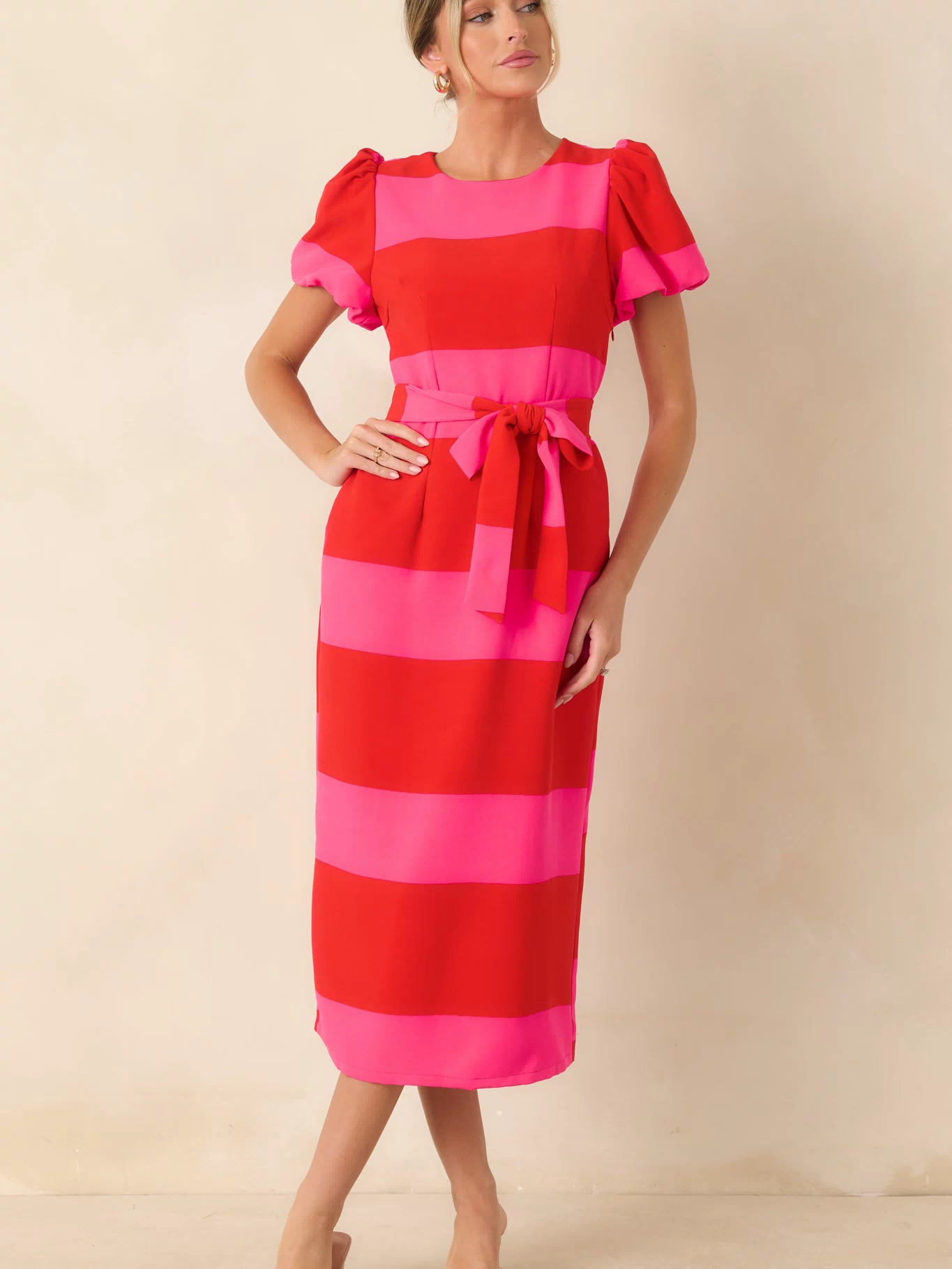 Striped midi dress featuring a round neckline, tailored fit, and vibrant red and pink color palette.