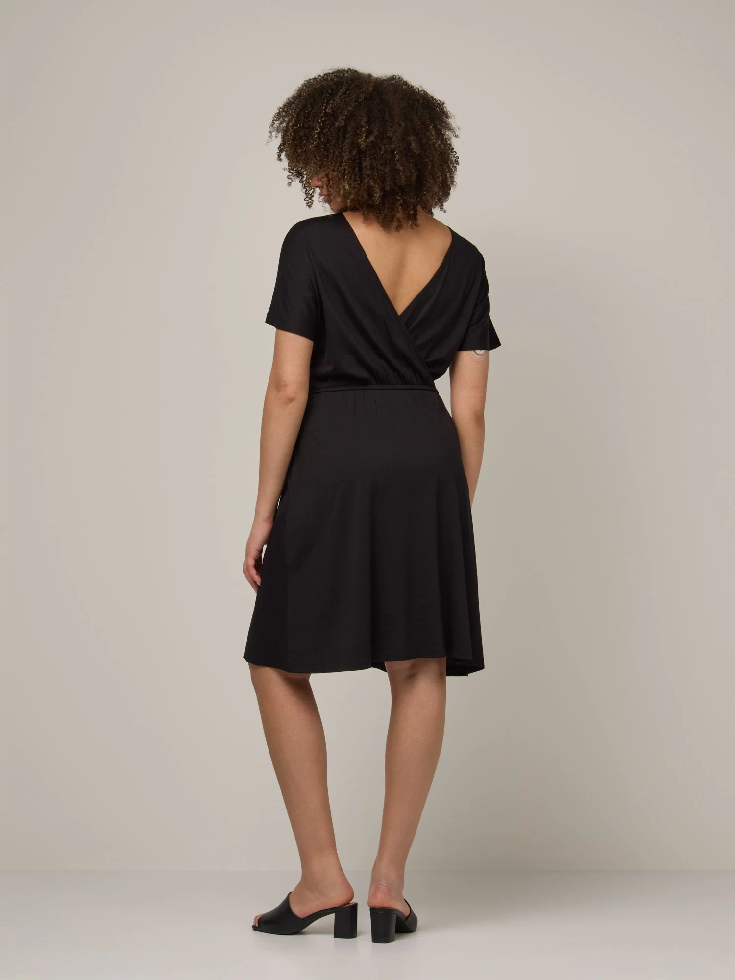 Model wearing Brooklyn Reversible Dress in Black. Brooklyn Reversible Dress is a merino wool short sleeve, reversible, knee length fit & flare dress with pockets available in sizes XS-3X Regular, XS-XL Long.