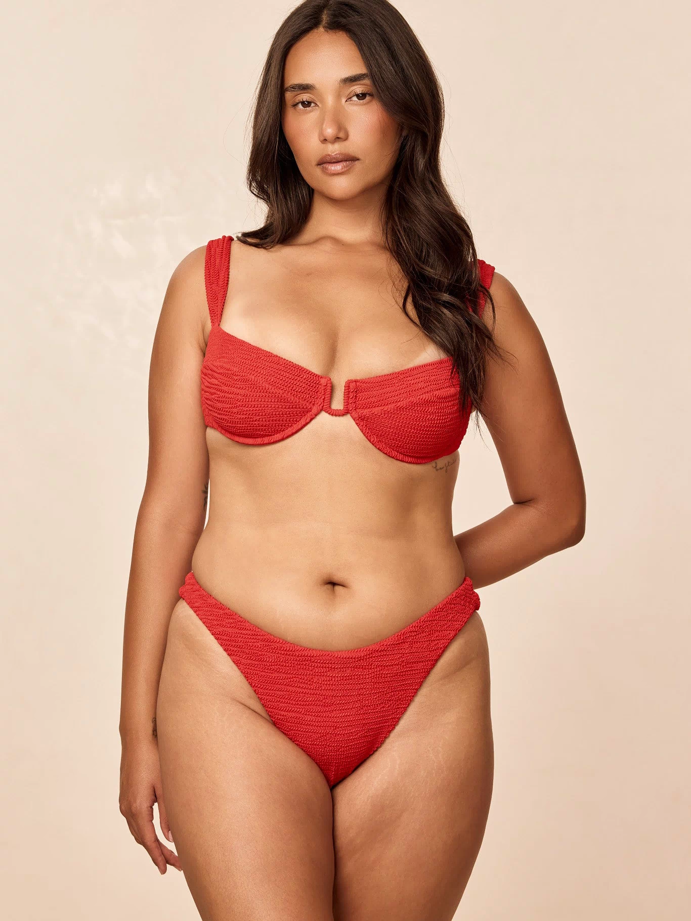 Front view of Byron Bottom in Chili Pepper Crinkle showing high-cut, textured red bikini bottom on model against beige background