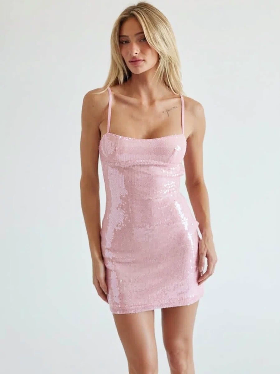 pink-image | A blonde model wearing a light pink sequined slip dress with spaghetti straps, standing against a plain light gray studio background.