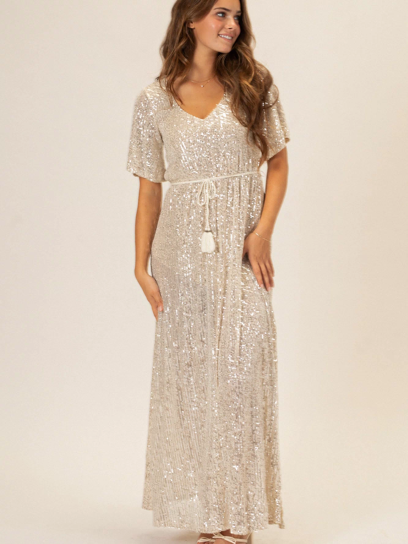 A silver sequin maxi dress with a v-neck and flared sleeves, creating a glamorous and sparkling evening look.