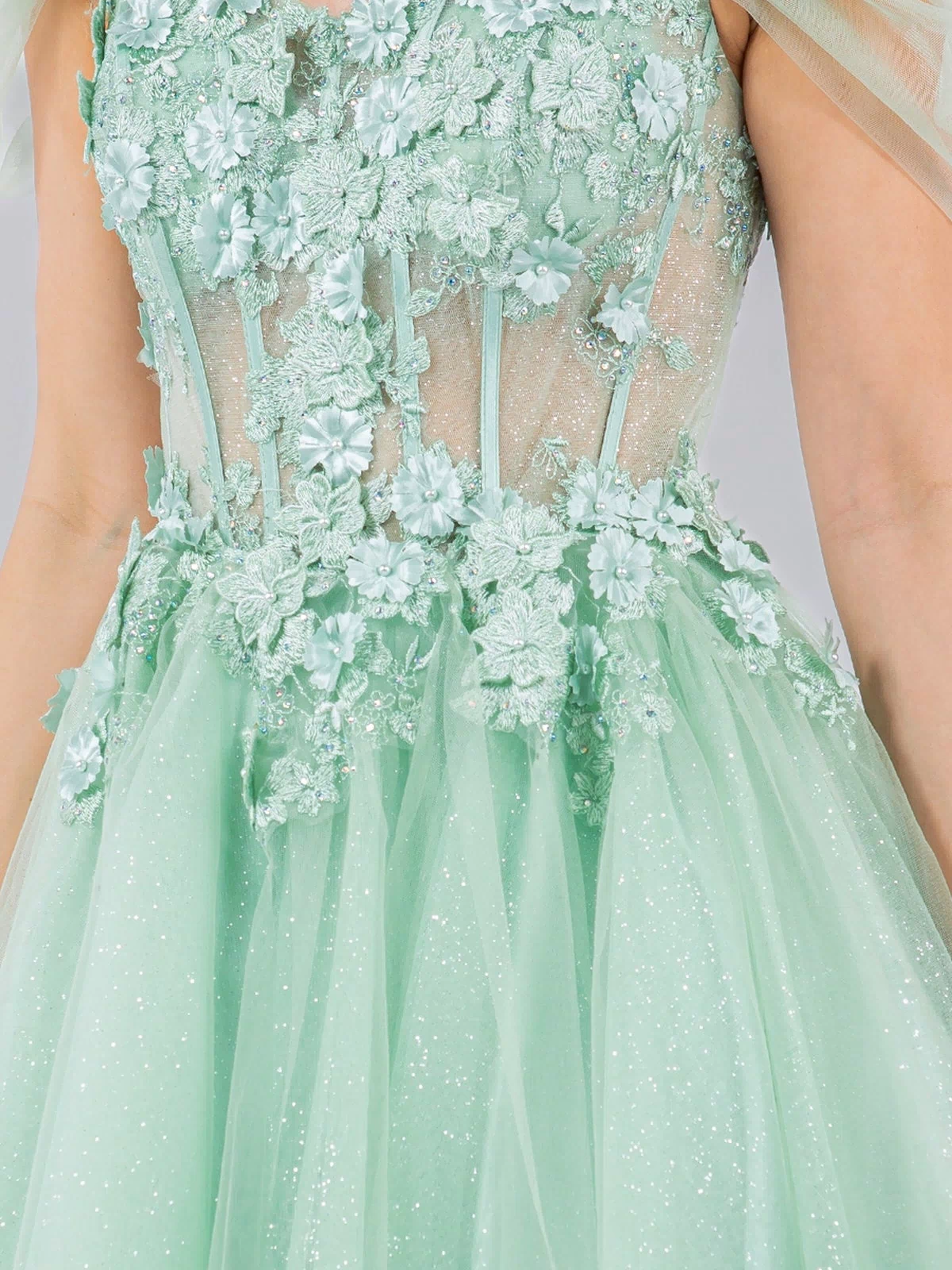 A close-up of the Embellished Short Glitter-Tulle Homecoming Dress in mint green, featuring floral appliqué, sheer bodice panels, off-shoulder tulle sleeves, and a sparkly tulle skirt.