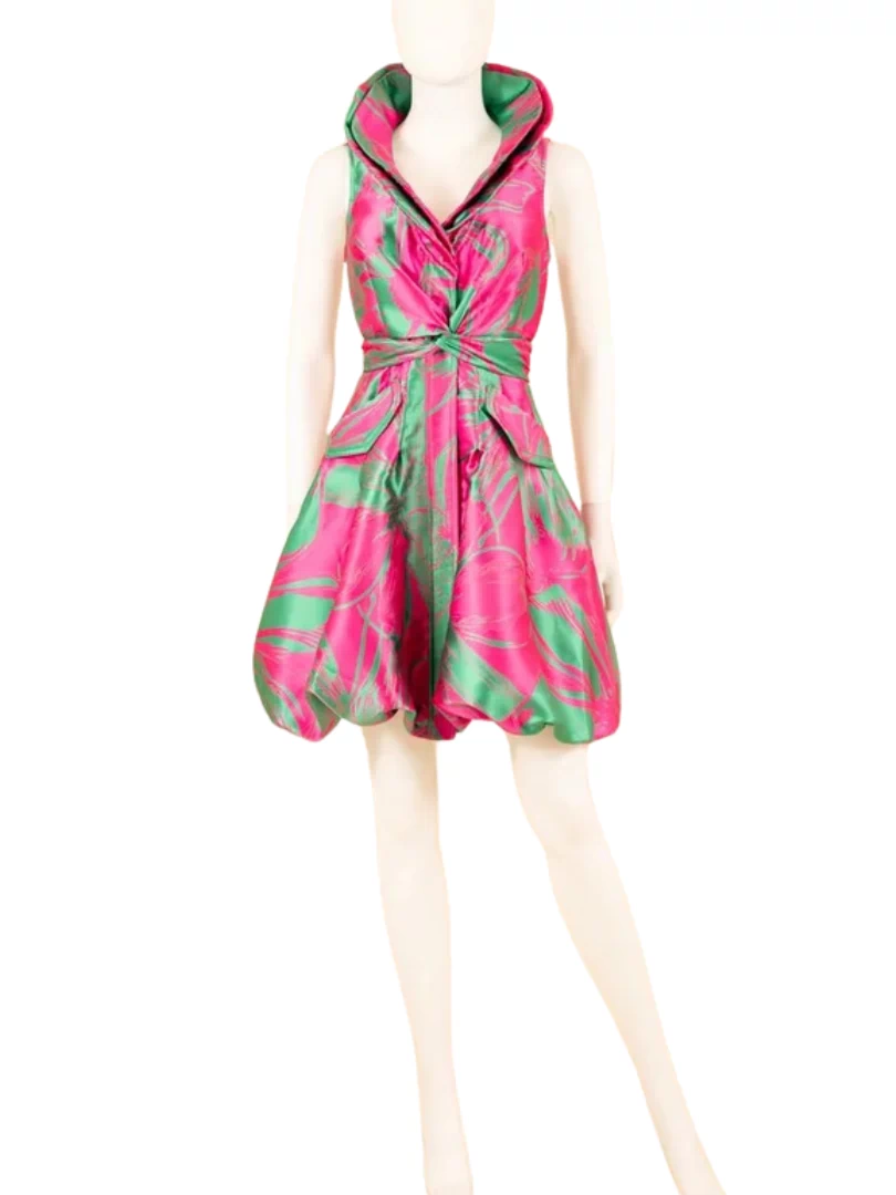 A stunning yarn-dyed brocade bubble dress displayed on a mannequin, featuring a wired collar with a cross-tie detail and a striking fuchsia and green color contrast.