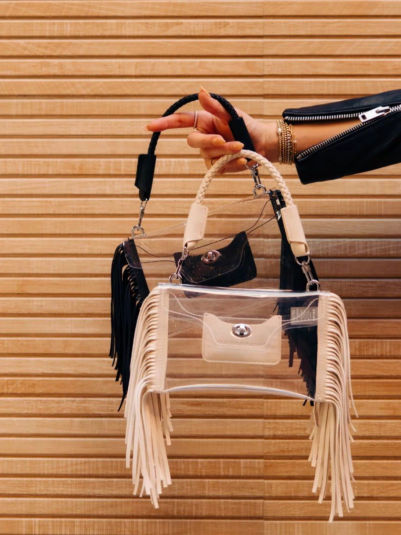 Woman holding Clear Fringe Crossbody in taupe and black - Margo Paige