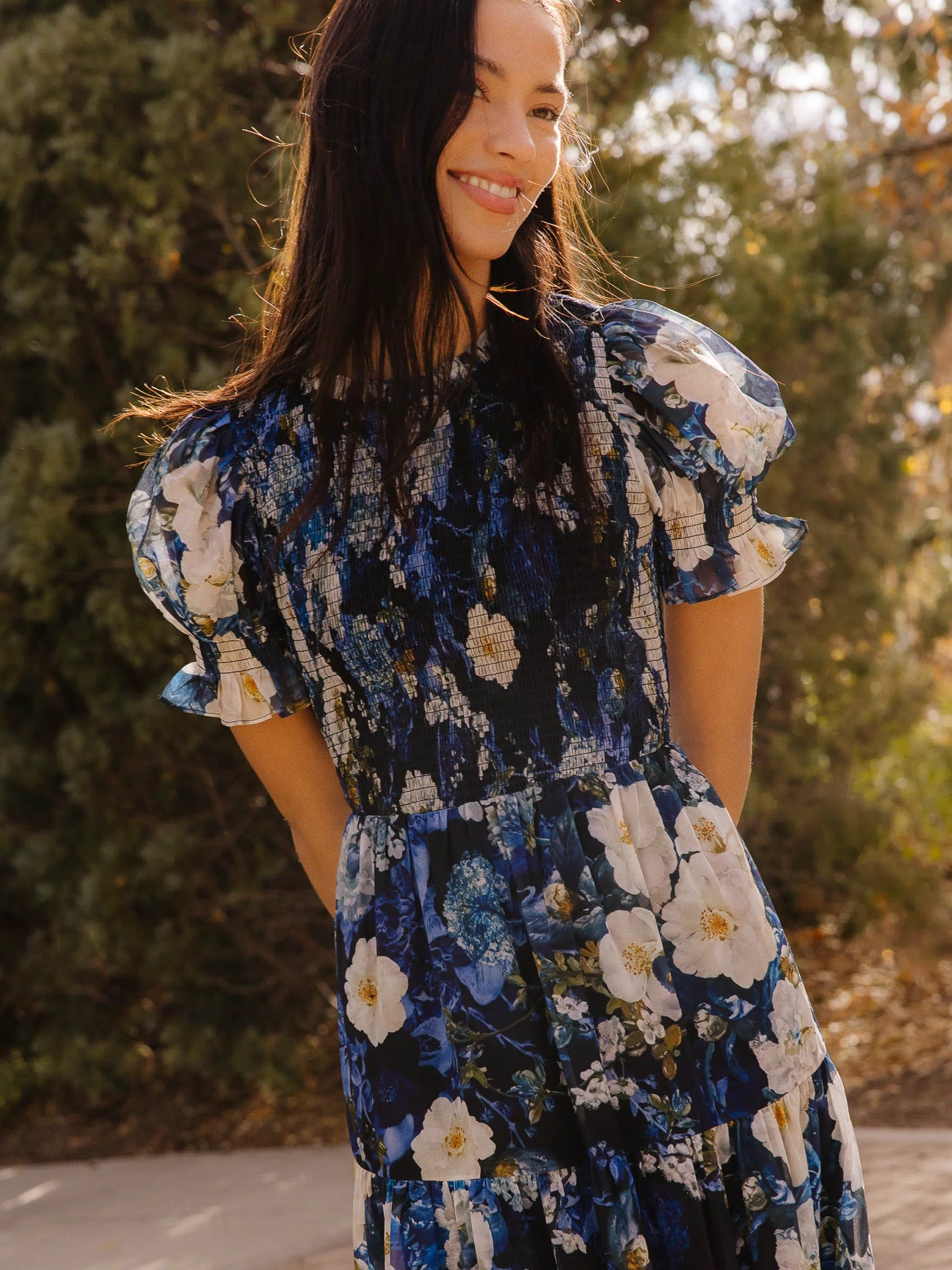 Girl in blue dress in front of trees