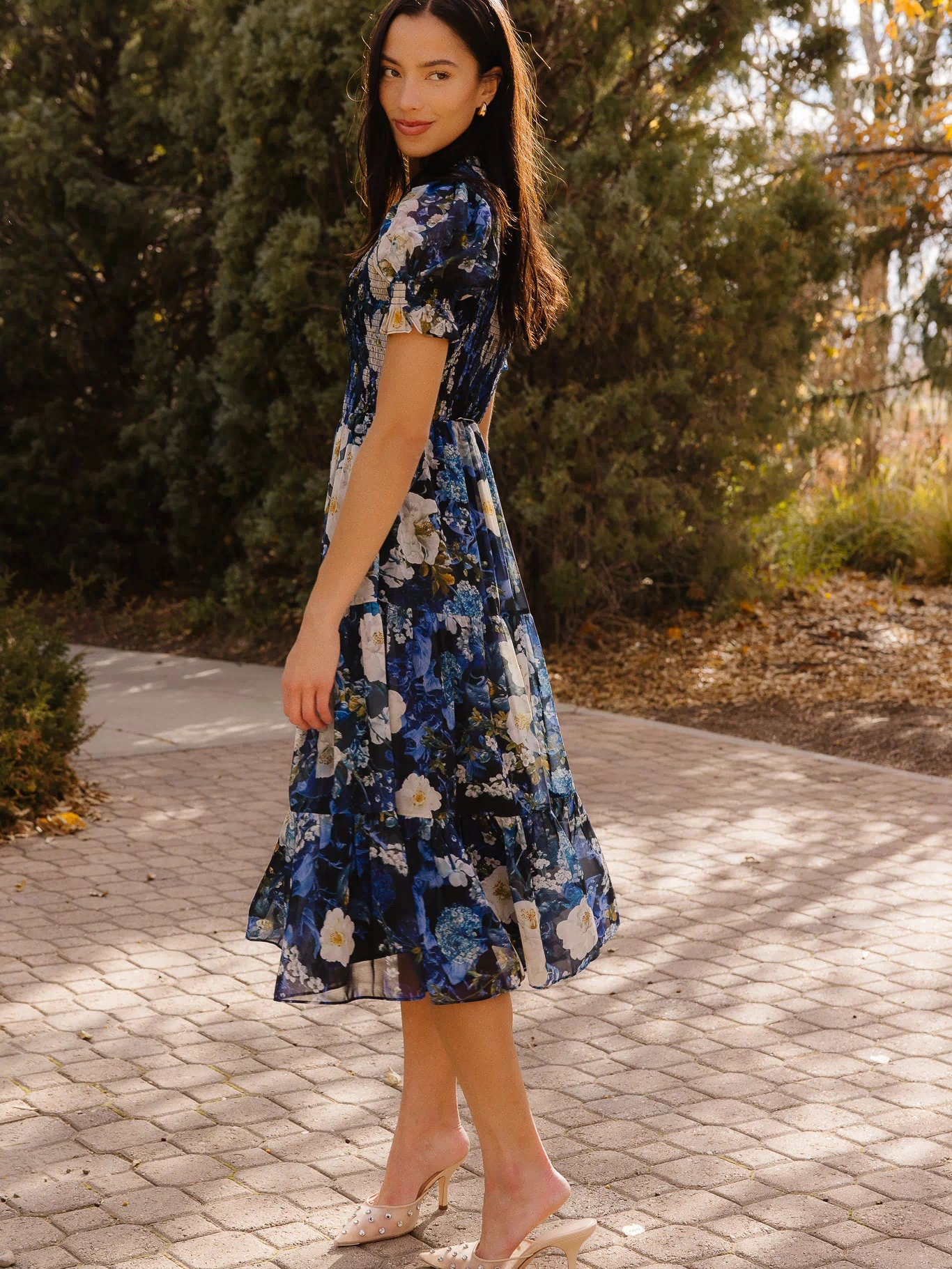 Girl in blue dress in front of trees