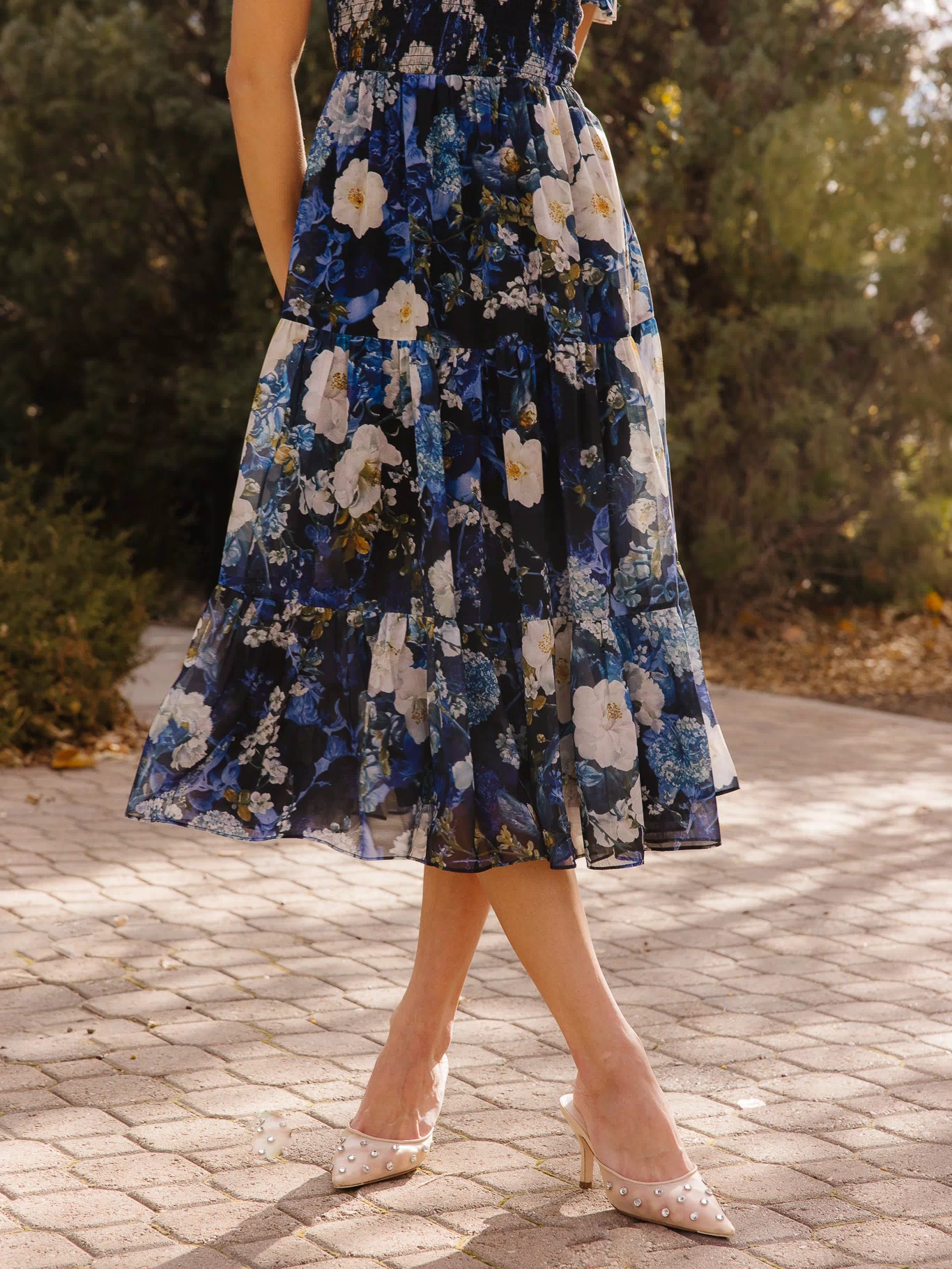 the bottom of a blue dress in front of trees