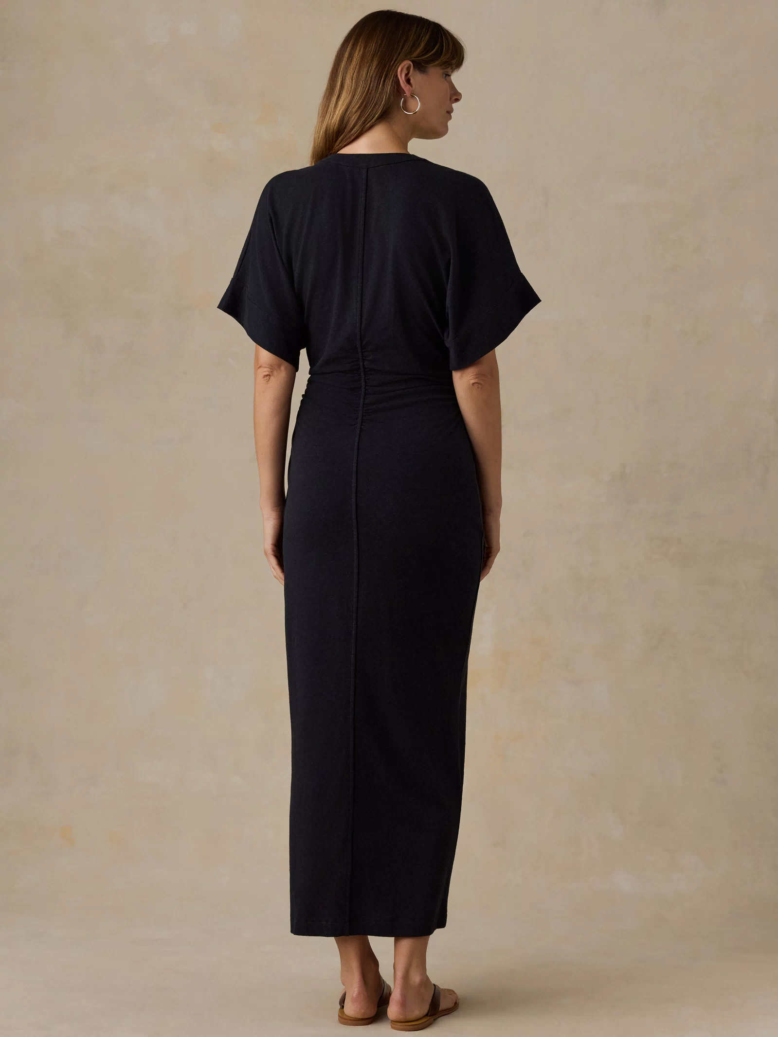 Woman wearing a black maxi dress against a beige background